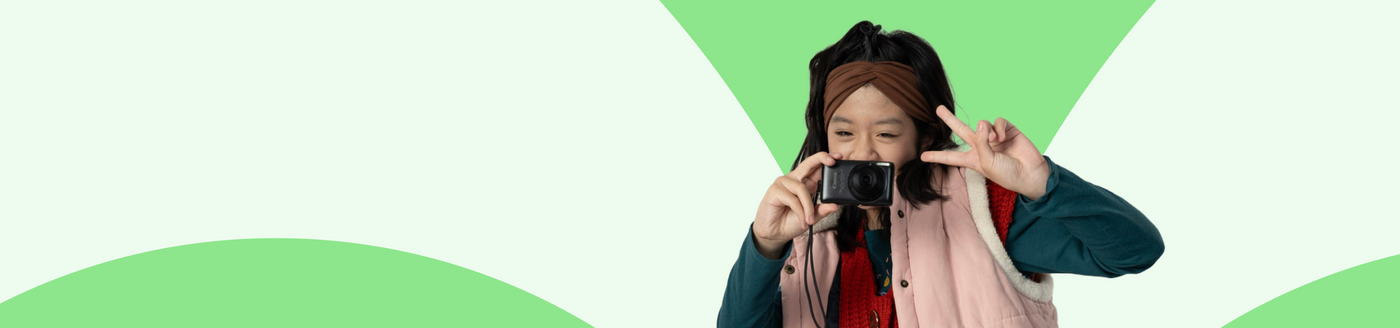 Person holding a camera against a green and white geometric background