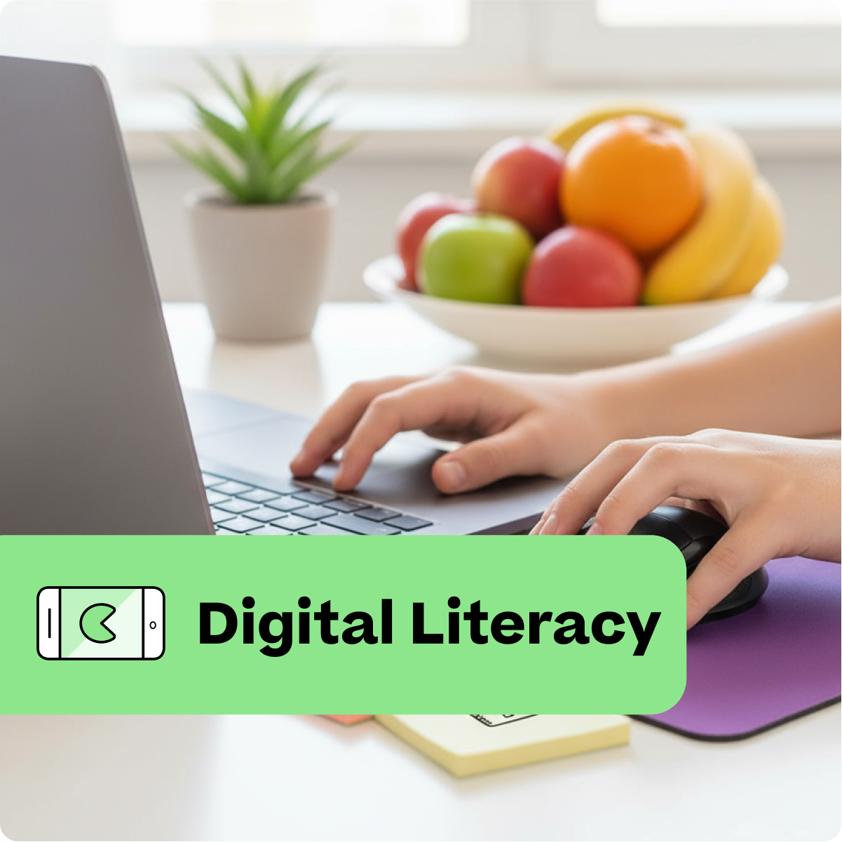Person using a laptop with a bowl of fruit on a desk, labeled 'Digital Literacy'.