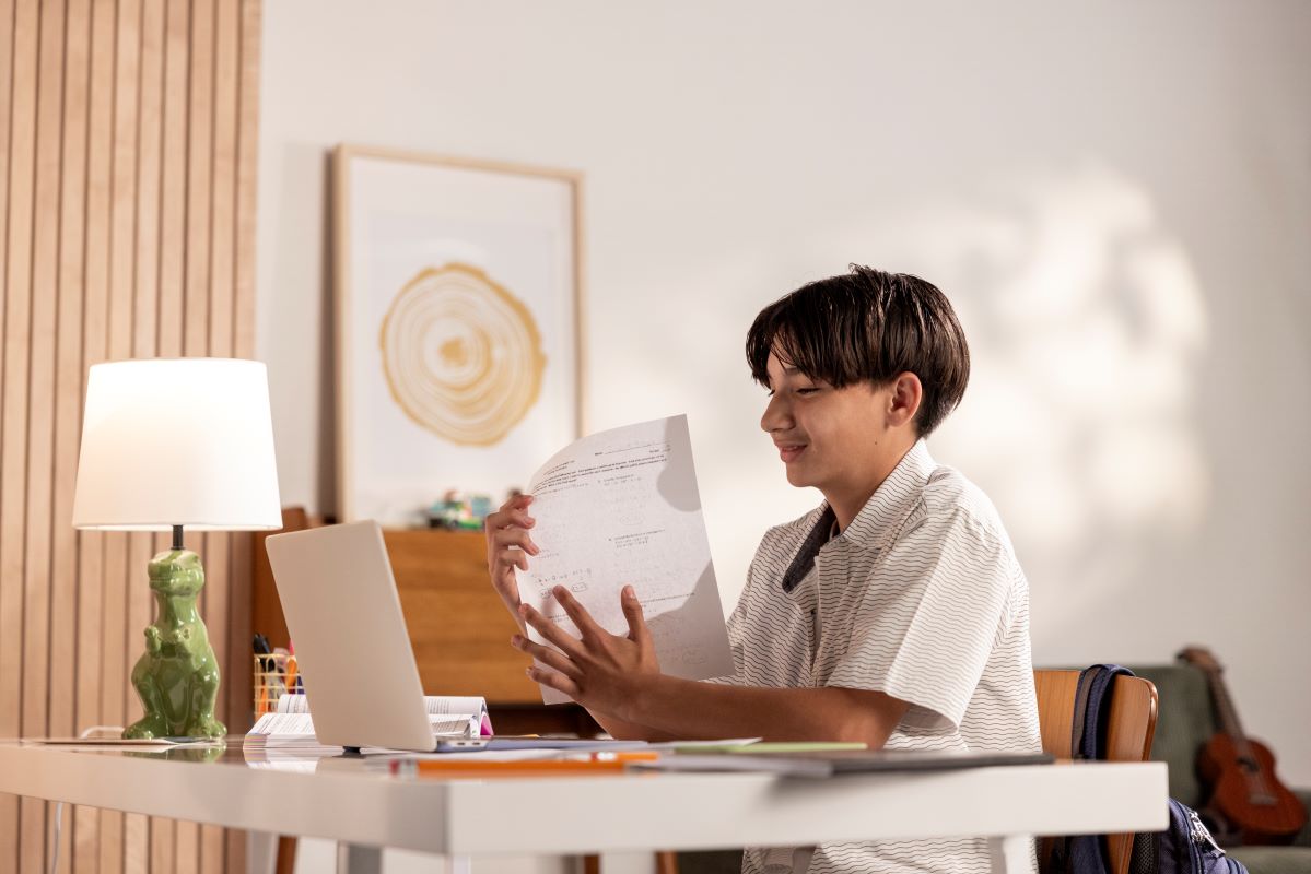 Person sitting at a desk holding papers in a home office setting